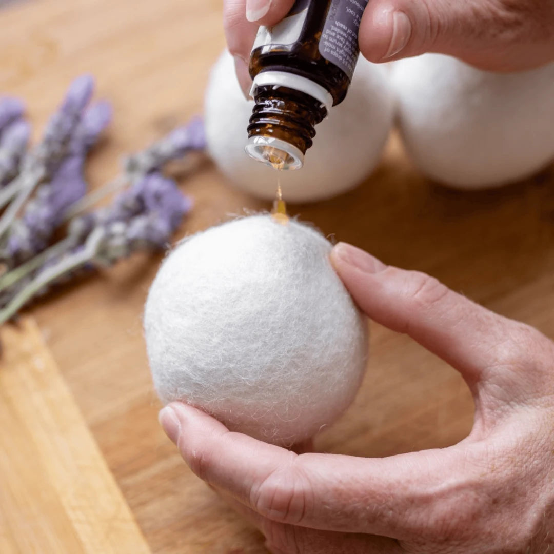a hand pouring some fragrance to a eco laundry dryer ball. | us and the