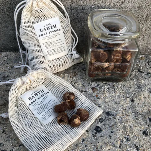 Soap berries for laundry presented in two pouches alongside a clear bottle, illustrating an eco-friendly laundry solution by Us and The Earth.