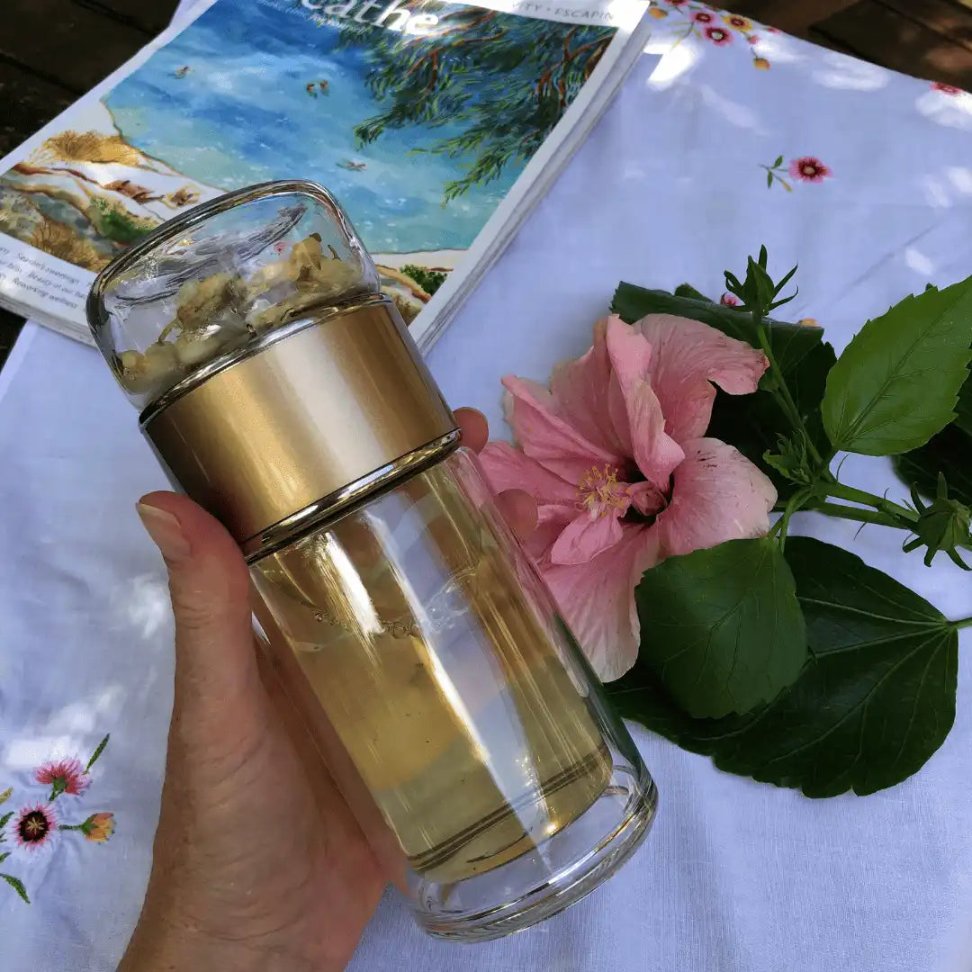 Gold tea bottle being shaken upside down for a refreshing tea experience on Us and The Earth.