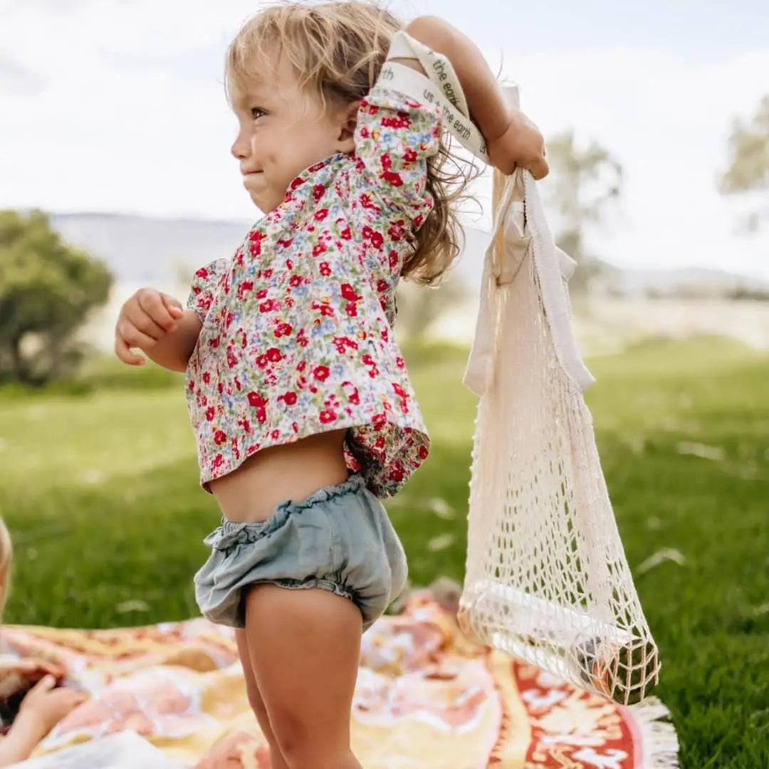 A child joyfully holding a Reusable Shopping Net Bag, highlighting eco-conscious habits.