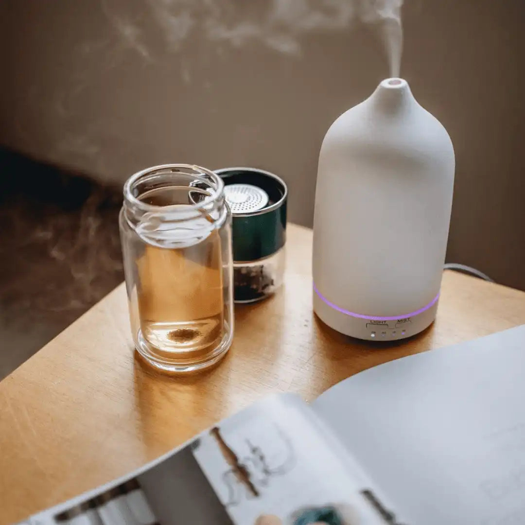 A lifestyle photo of our double wall tea bottle without the lid and beside our stone aroma and essential oil diffuser.