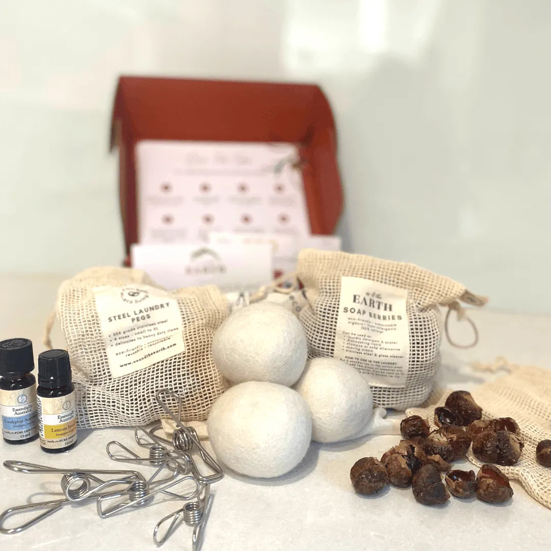 The products inside the Us and the Earth Eco Laundry Box - 16 pieces stainless steel pegs, 4 pieces a merino wool dryer balls, 250g soap nuts in a branded mesh bag and Essential oils from Essentially Australia