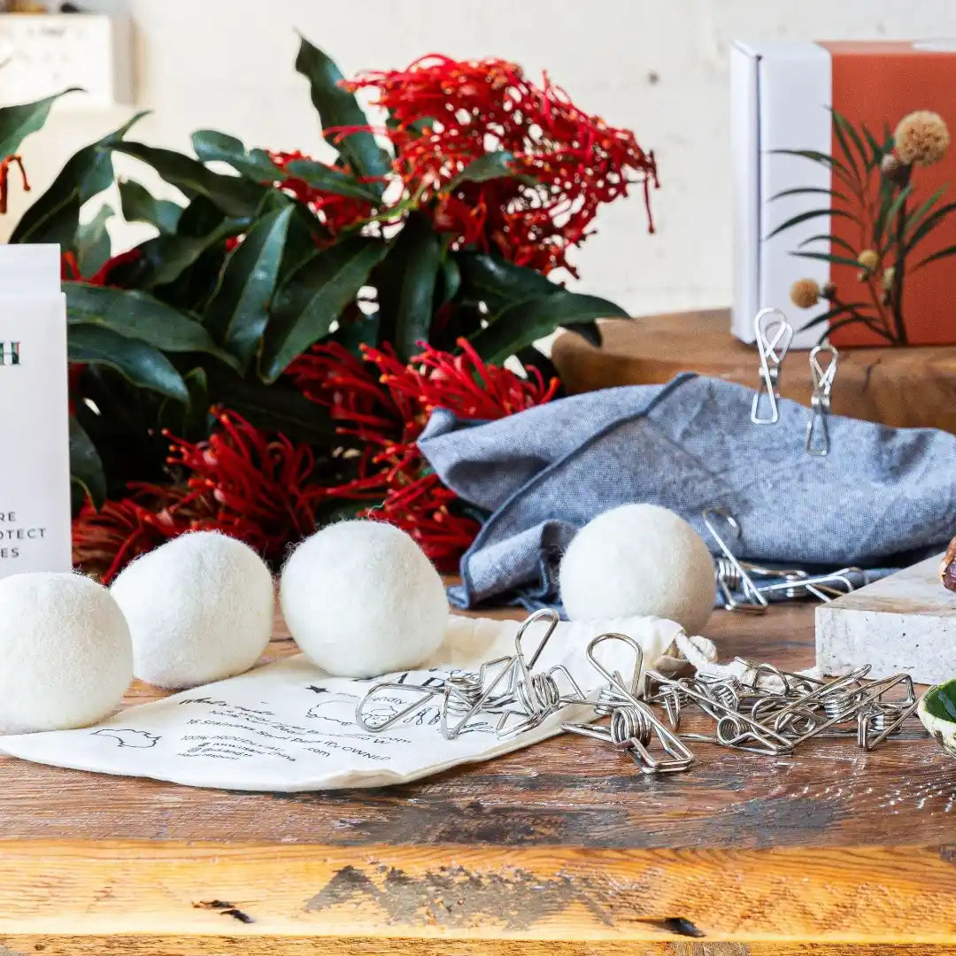 dryer balls and pegs scatter on the table, with some flowers in the back | us and the earth
