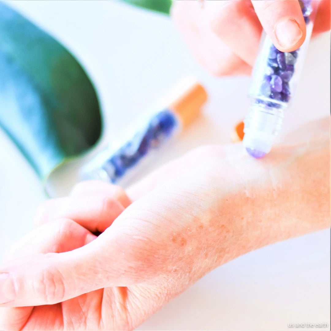An image featuring a 10ml essential oil crystal gemstone roller bottle being rubbed on a hand, part of the Eco Lifestyle collection from - Us and The Earth.