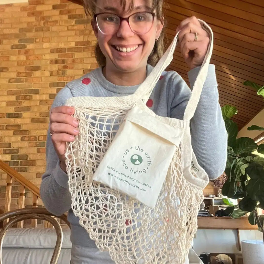 A person holding a Reusable Shopping Net Bag with a convenient pocket, showcasing its practicality and eco-friendliness.